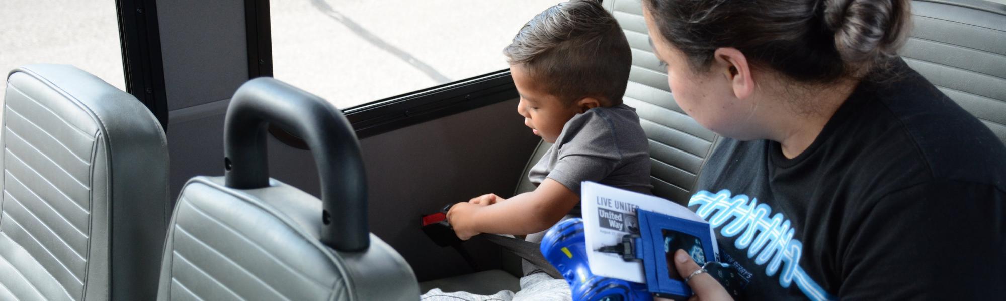 Preschool boy buckling his seatbelt on the bus.